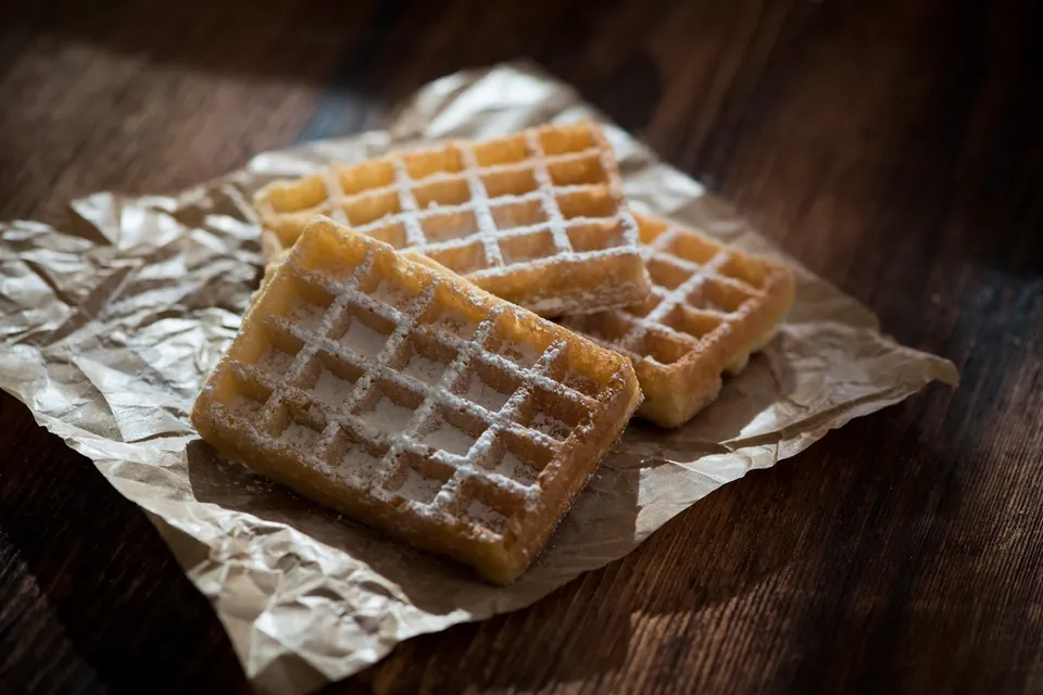 Square waffles dusted with sugar on crumpled baking paper