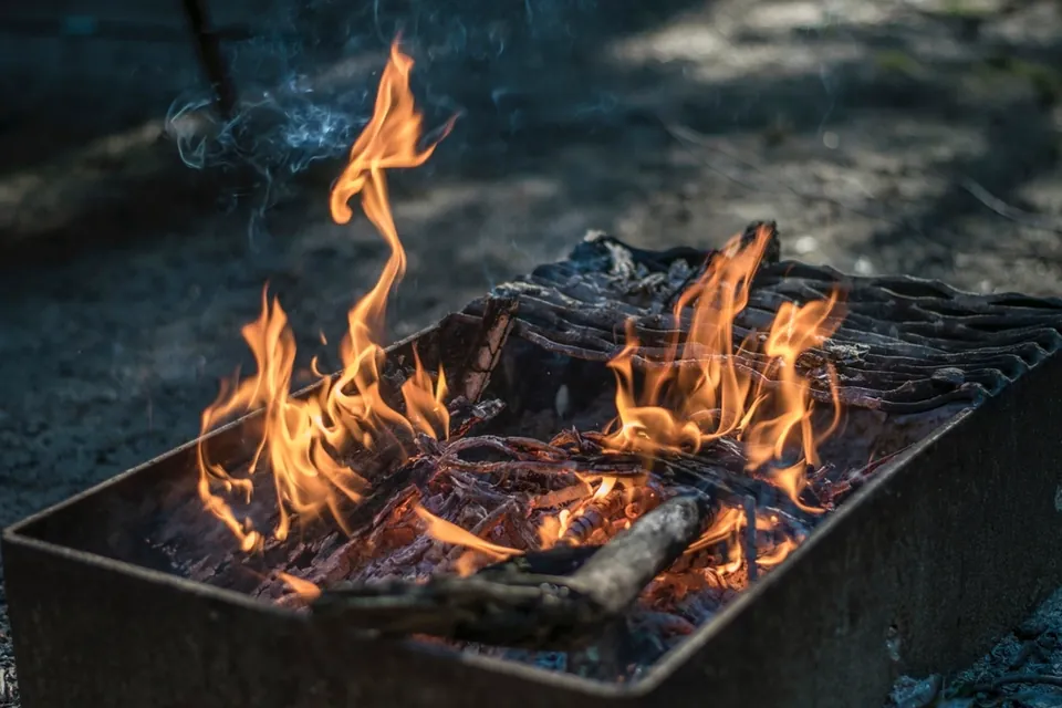 Flames rising from burning wood and charcoal in a grill