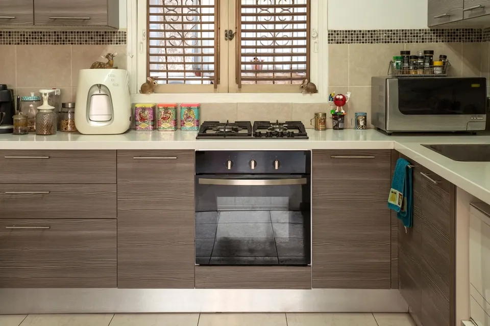 A bright, empty fitted kitchen with a hob, oven and wall cupboards